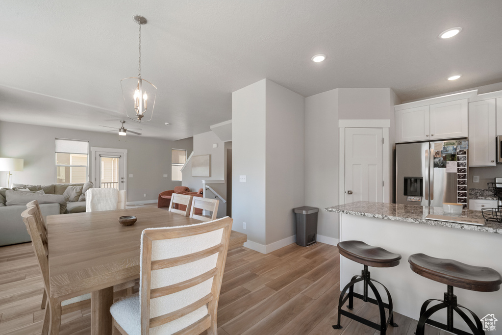 Dining area with light wood finished floors, recessed lighting, a ceiling fan, and a chandelier