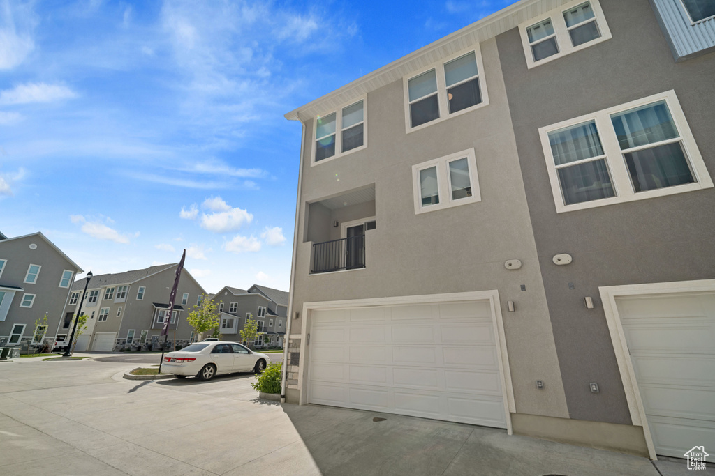 View of front of house featuring stucco siding, an attached garage, and a residential view