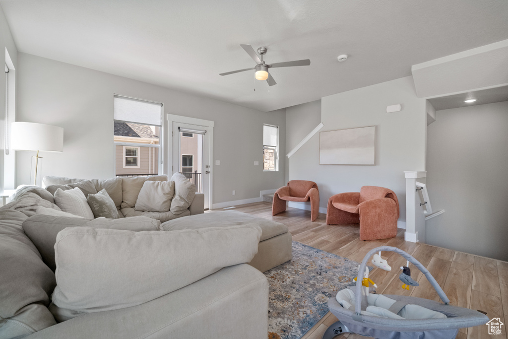 Living room with wood finished floors, healthy amount of natural light, and ceiling fan