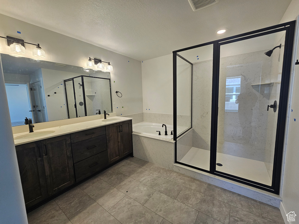 Bathroom with a bath, a shower stall, double vanity, a textured ceiling, and tile patterned flooring