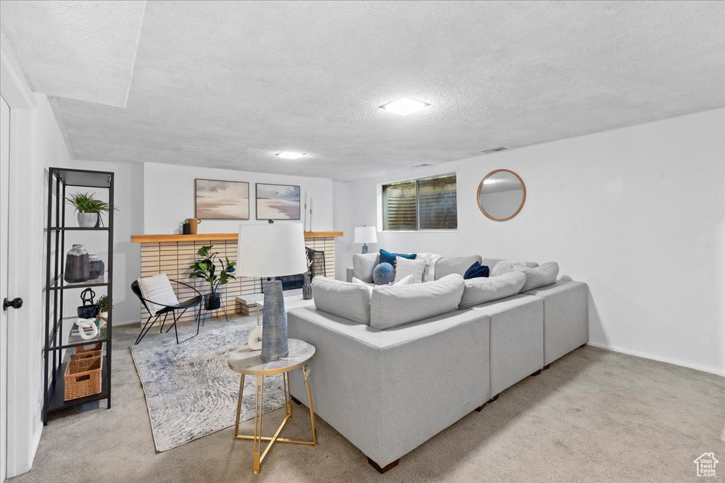 Living room with a textured ceiling, a fireplace, and carpet