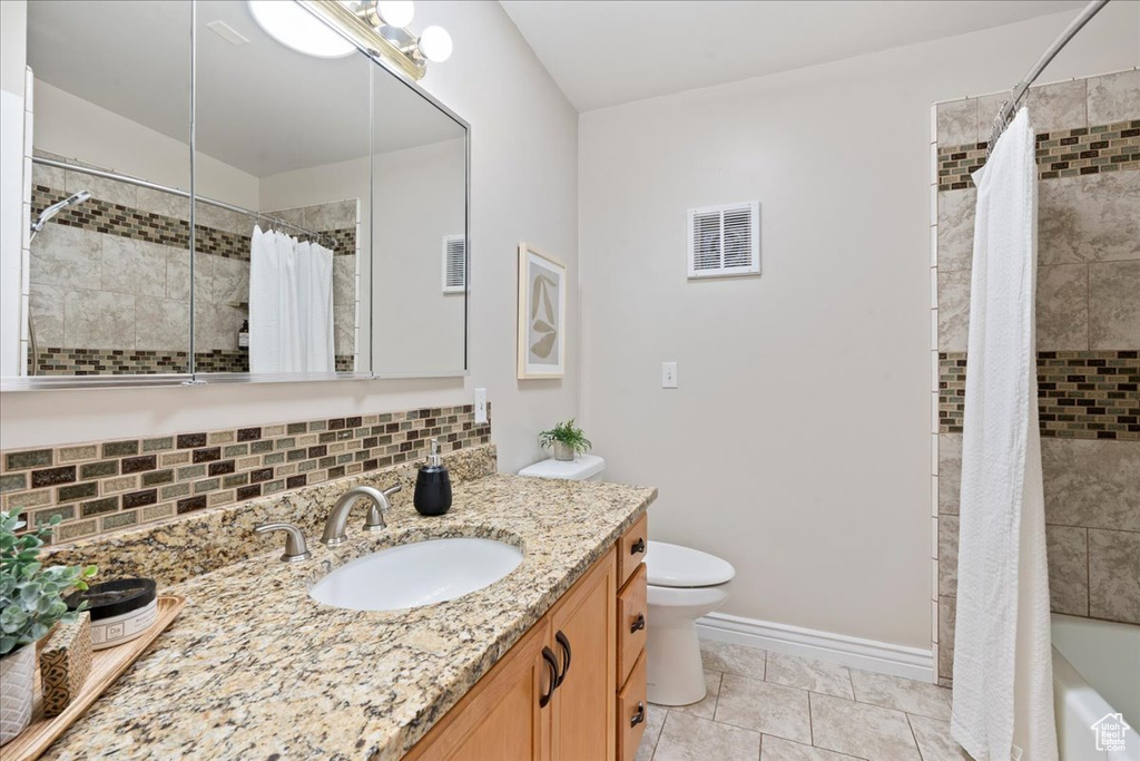 Bathroom featuring vanity, decorative backsplash, shower / tub combo, and tile patterned floors