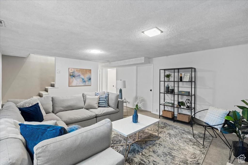 Living room with stairs, a textured ceiling, and carpet