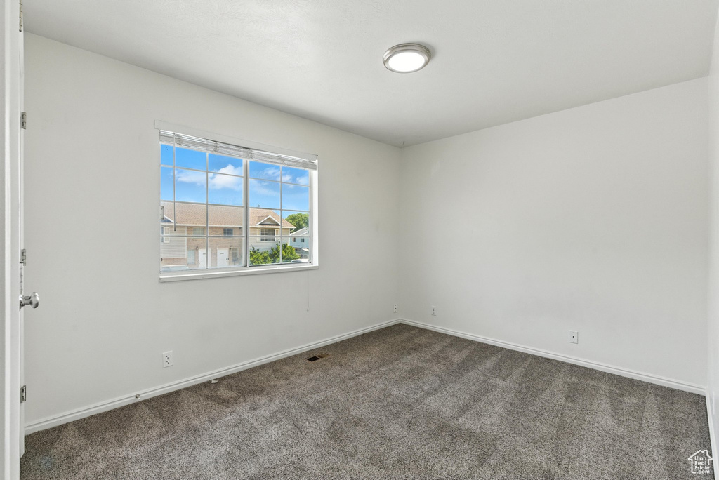 Unfurnished room featuring dark carpet and baseboards