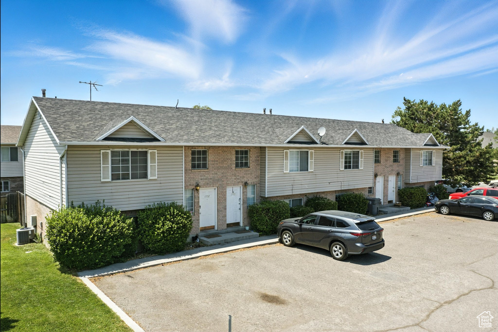 Raised ranch featuring uncovered parking, brick siding, and a shingled roof