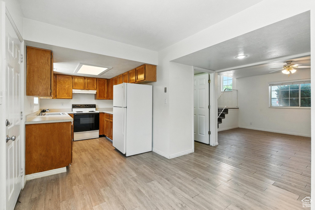 Kitchen with white appliances, brown cabinets, light countertops, and light wood finished floors