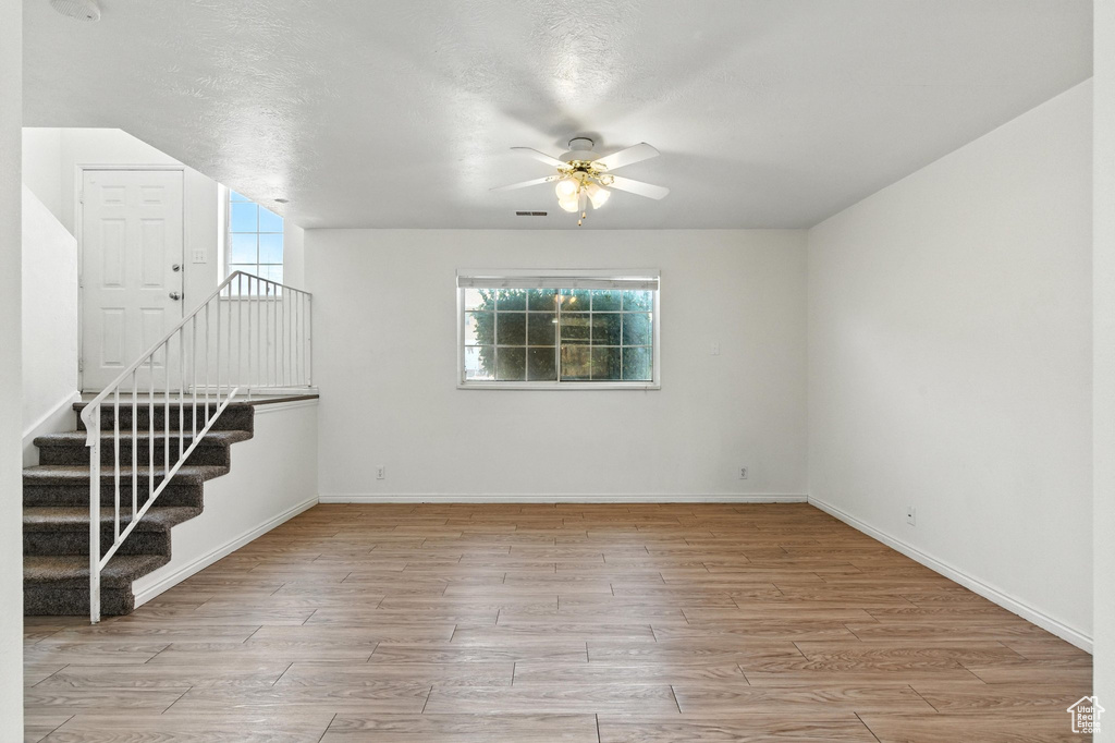 Empty room with ceiling fan, healthy amount of natural light, and wood finished floors