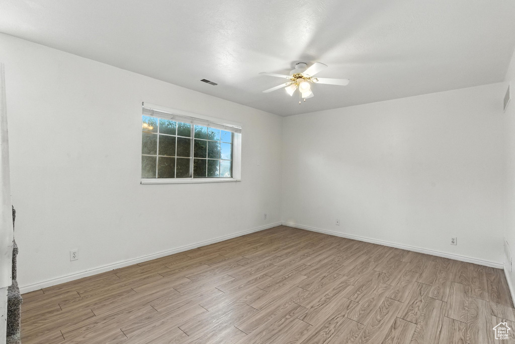Spare room with light wood finished floors and a ceiling fan