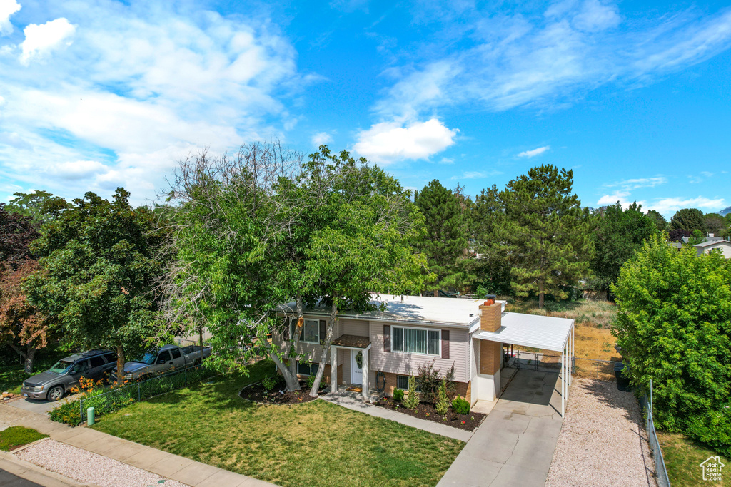 View of front of home featuring concrete driveway, an attached carport, and a chimney