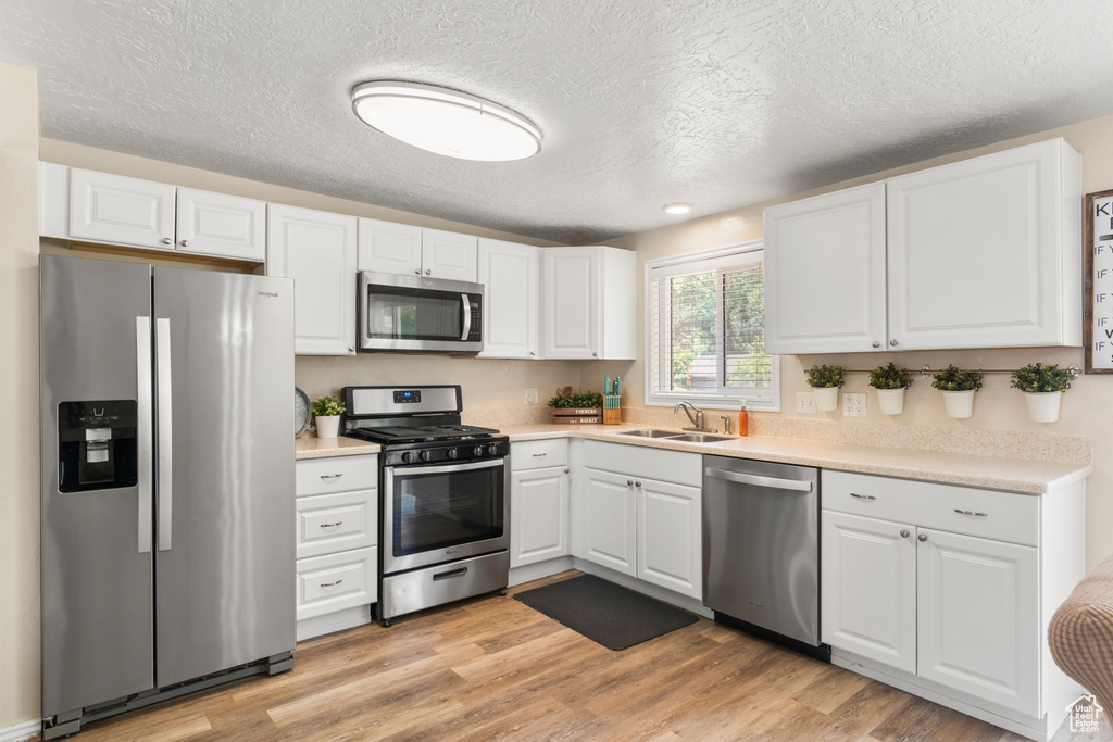 Kitchen featuring appliances with stainless steel finishes, white cabinets, and a textured ceiling