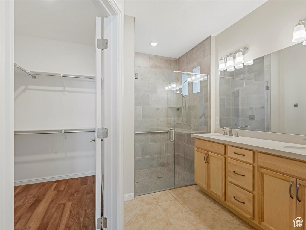 Bathroom featuring a walk in closet, double vanity, a shower stall, and recessed lighting