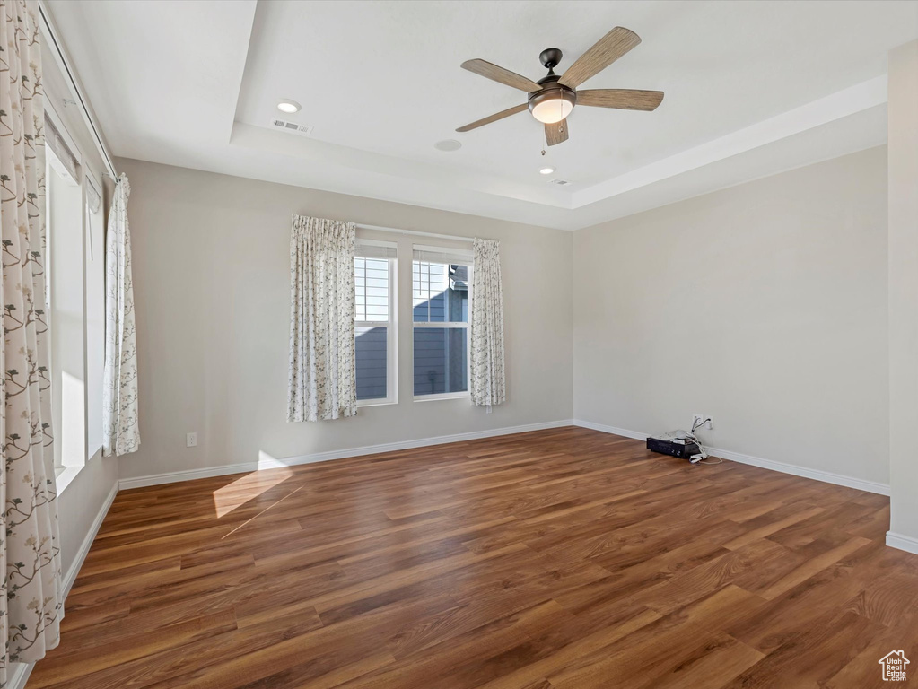 Unfurnished room with a tray ceiling, a ceiling fan, wood finished floors, and recessed lighting