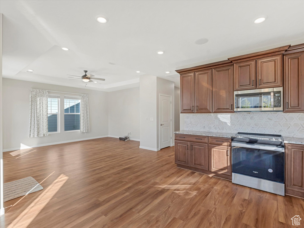 Kitchen featuring appliances with stainless steel finishes, backsplash, light wood-type flooring, recessed lighting, and a ceiling fan