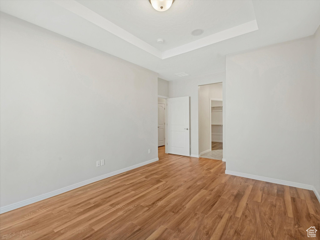 Unfurnished room featuring light wood-style floors and a raised ceiling