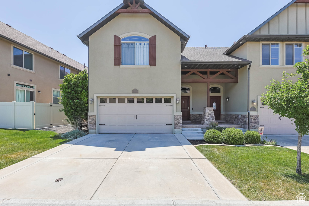 View of front of home featuring stone siding, a garage, concrete driveway, and stucco siding