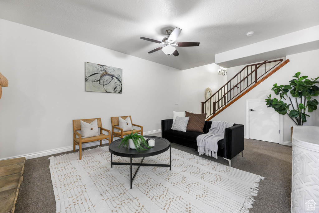 Carpeted living room with stairs and ceiling fan