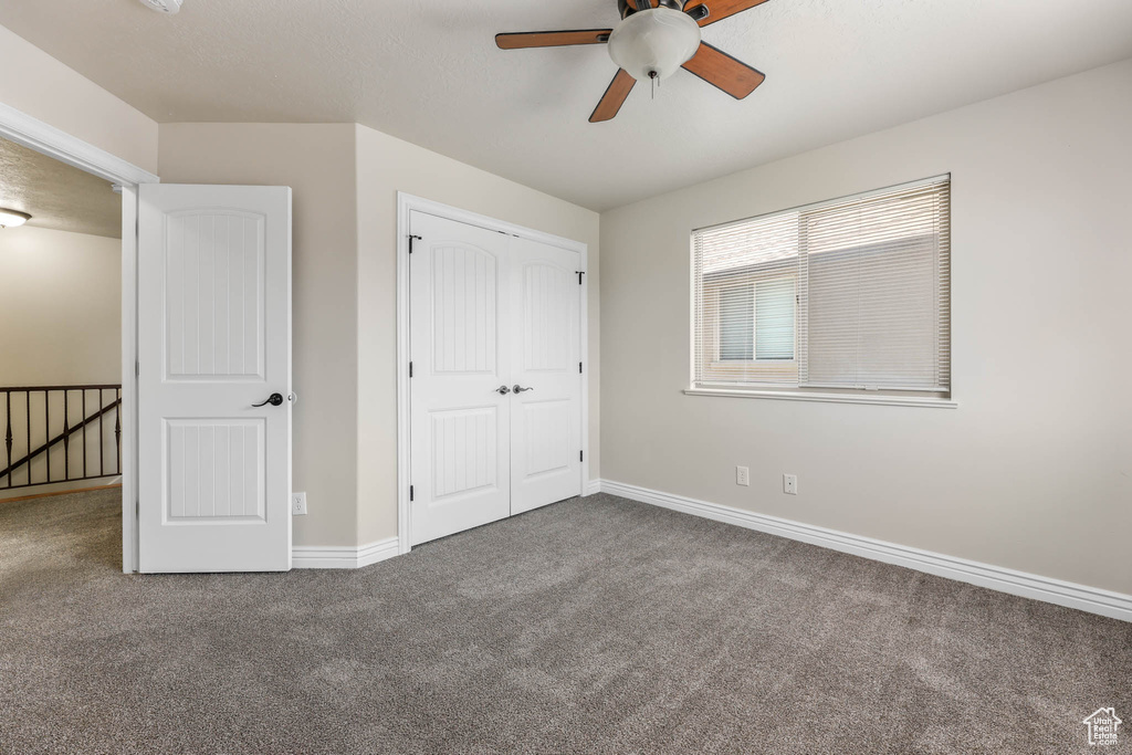 Unfurnished bedroom with carpet, a closet, and a ceiling fan
