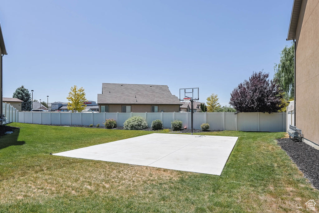 View of basketball court featuring a fenced backyard and basketball hoop