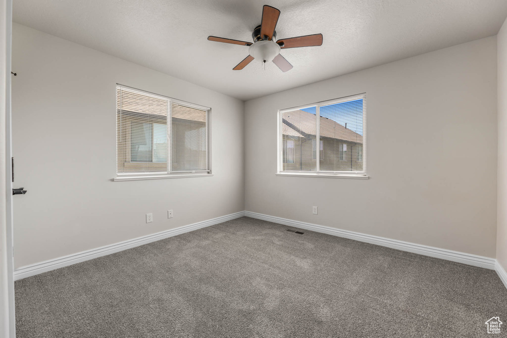 Carpeted spare room with a ceiling fan and baseboards