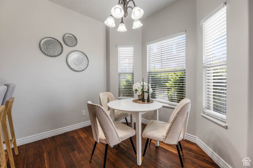 Dining space with dark wood-type flooring and a chandelier