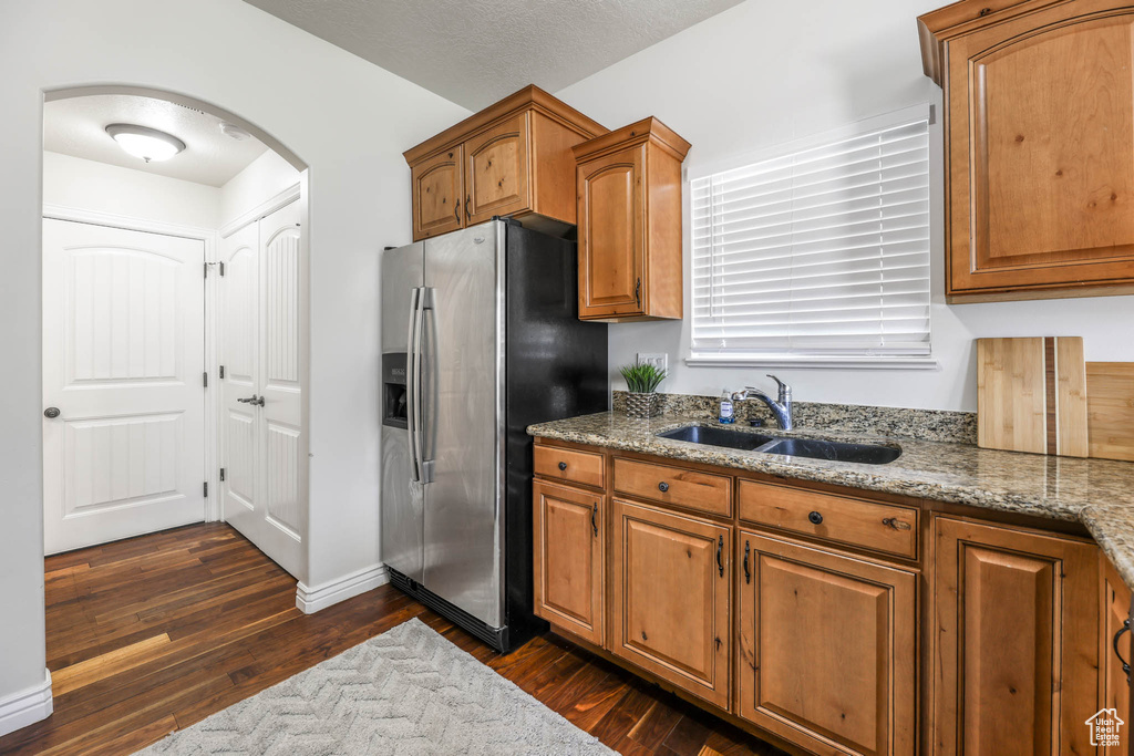 Kitchen with stainless steel fridge, arched walkways, and brown cabinets