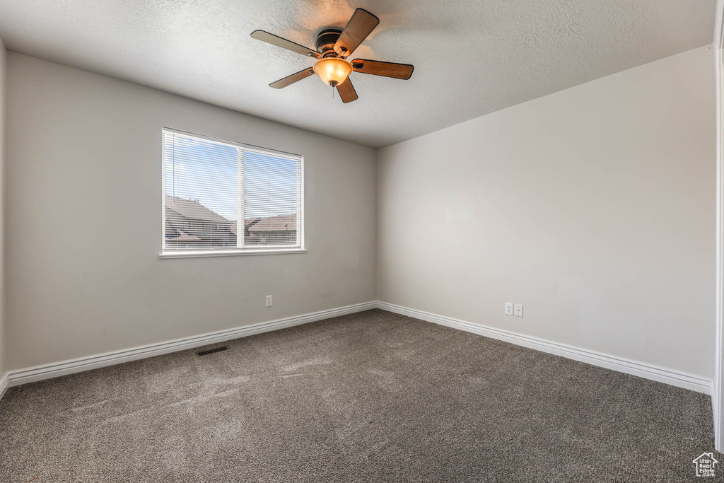 Empty room featuring ceiling fan, carpet flooring, and a textured ceiling