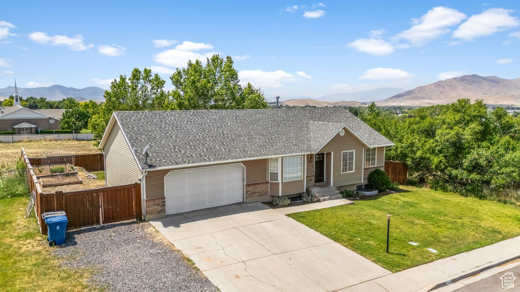 Ranch-style home featuring a garage, a mountain view, concrete driveway, and a shingled roof