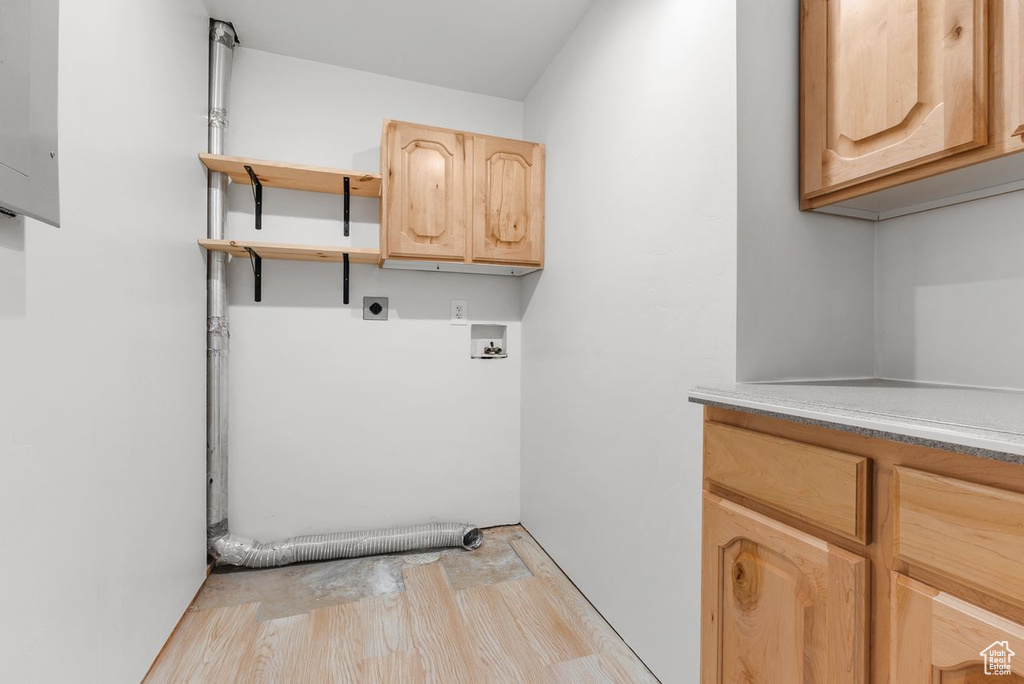 Washroom with cabinet space, hookup for an electric dryer, light wood-style floors, and washer hookup