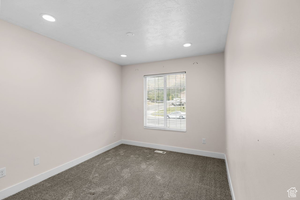 Spare room featuring dark carpet and recessed lighting
