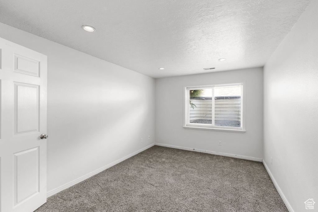 Carpeted empty room featuring a textured ceiling and recessed lighting