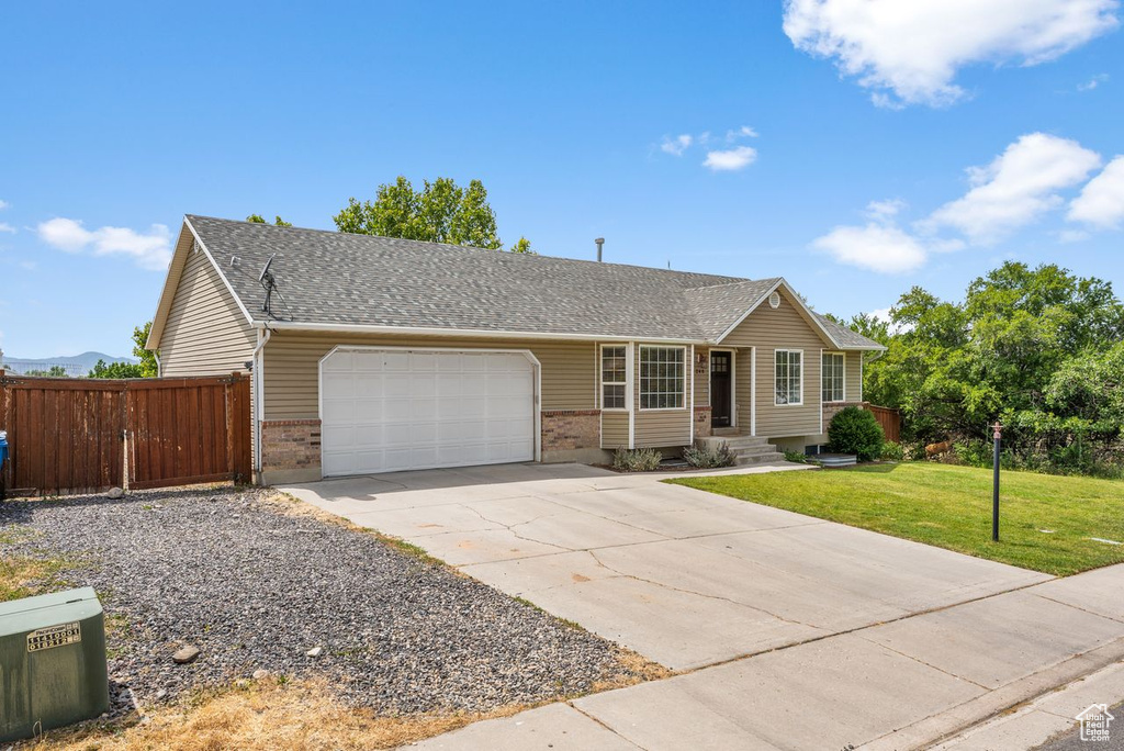 Ranch-style house featuring brick siding, an attached garage, driveway, and a shingled roof