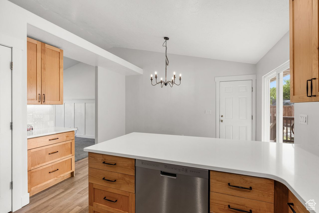 Kitchen featuring stainless steel dishwasher, vaulted ceiling, light wood-style floors, light countertops, and a peninsula