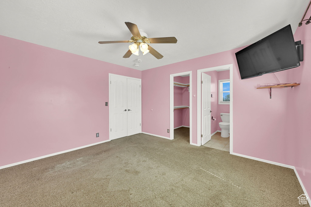 Unfurnished bedroom featuring carpet flooring, a ceiling fan, and ensuite bathroom