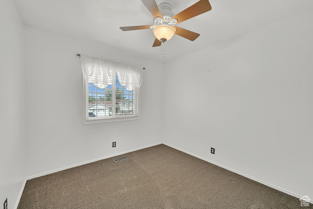 Spare room with dark colored carpet and a ceiling fan