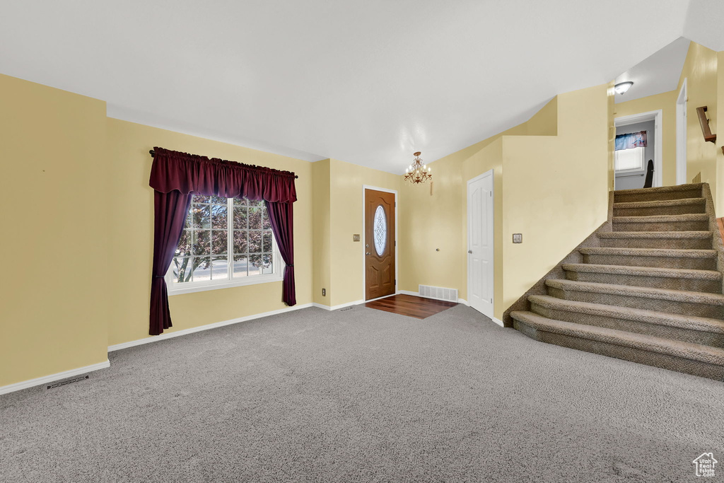 Carpeted foyer with a chandelier and stairway