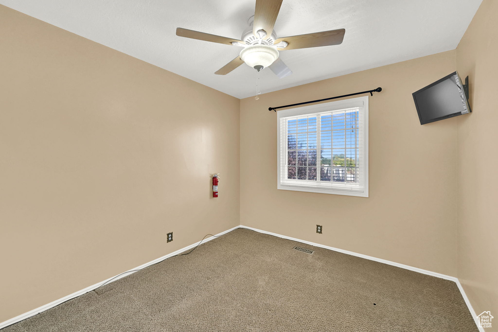 Carpeted empty room featuring a ceiling fan and baseboards