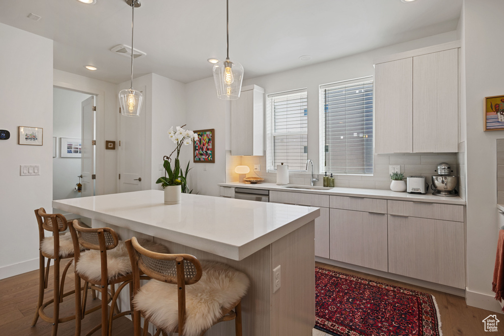 Kitchen featuring light wood-style floors, a kitchen bar, tasteful backsplash, recessed lighting, and light countertops