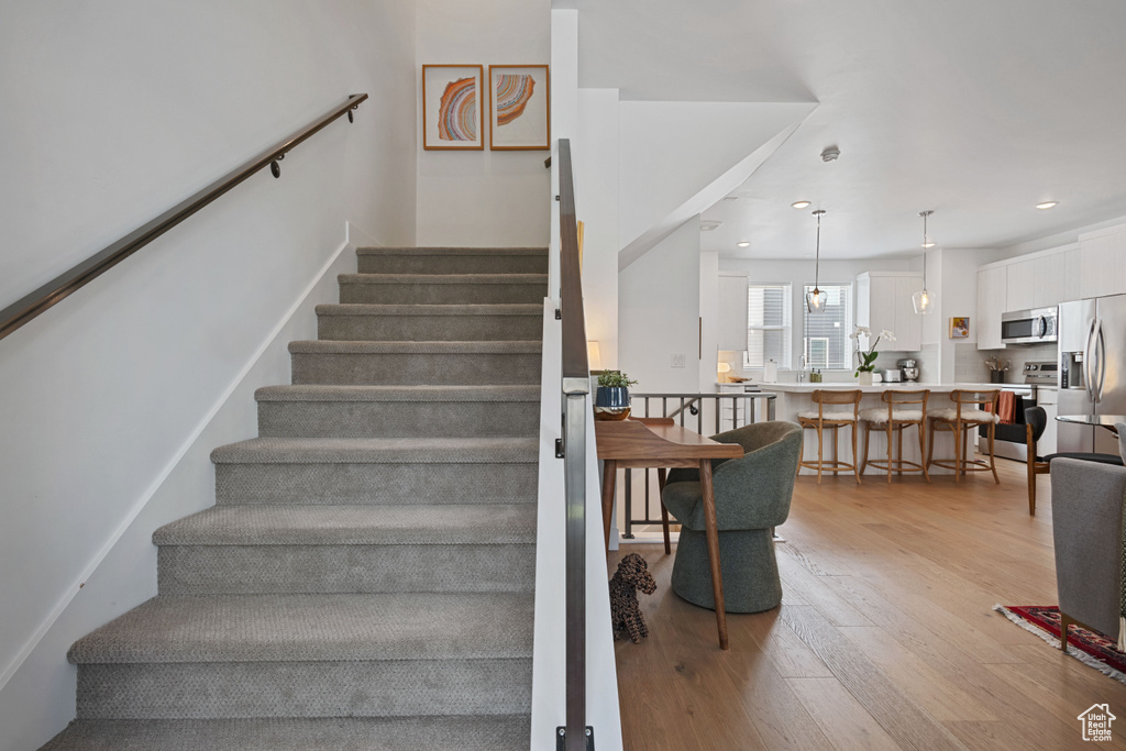 Stairs featuring wood finished floors and recessed lighting