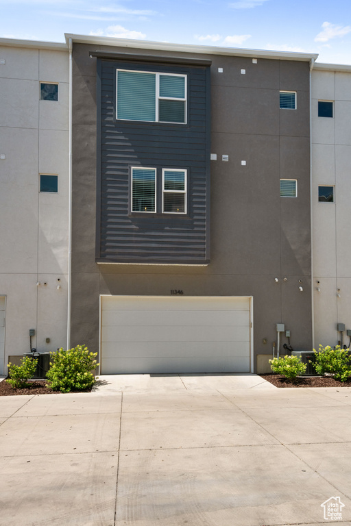 View of front facade featuring driveway, a garage, and stucco siding