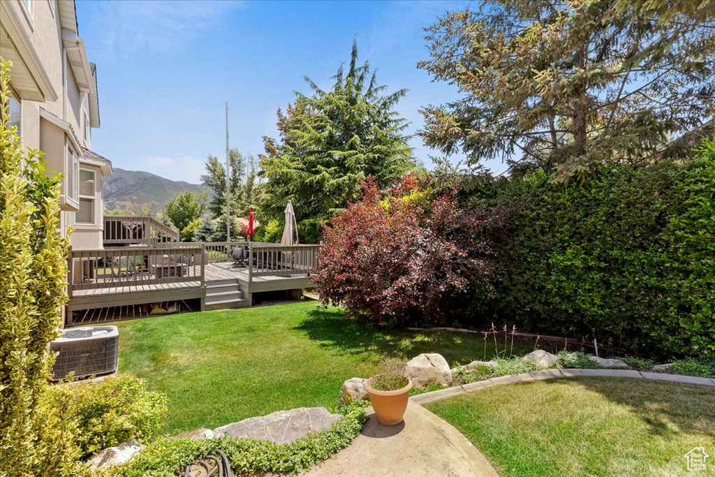 View of green lawn with a deck with mountain view