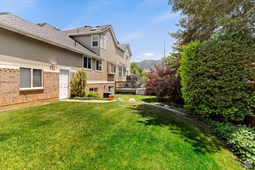 View of green lawn with a deck with mountain view