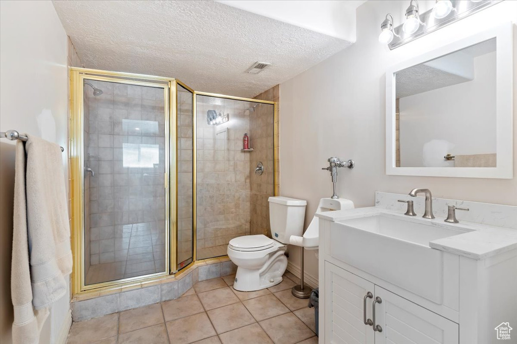 Bathroom featuring vanity, a stall shower, tile patterned flooring, and a textured ceiling