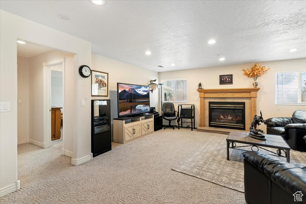 Living area featuring recessed lighting, light carpet, a glass covered fireplace, and a textured ceiling
