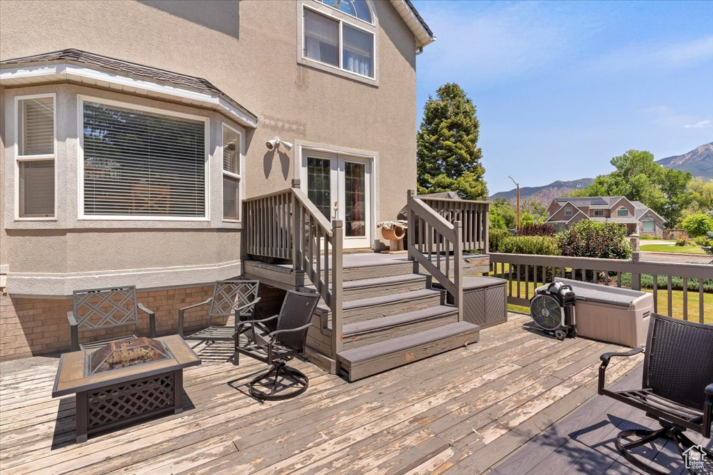 Wooden deck featuring a fire pit, a mountain view, and french doors