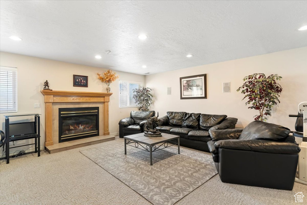 Carpeted living room featuring a glass covered fireplace, recessed lighting, and a textured ceiling