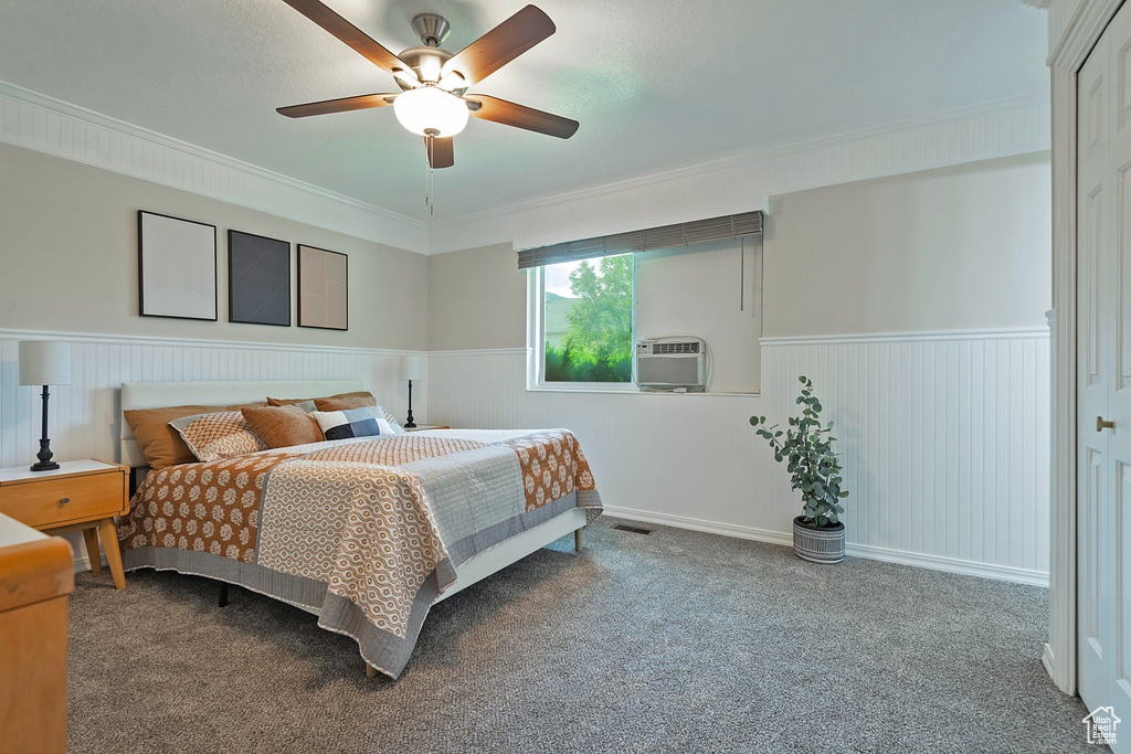 Carpeted bedroom featuring wainscoting, ornamental molding, ceiling fan, and cooling unit