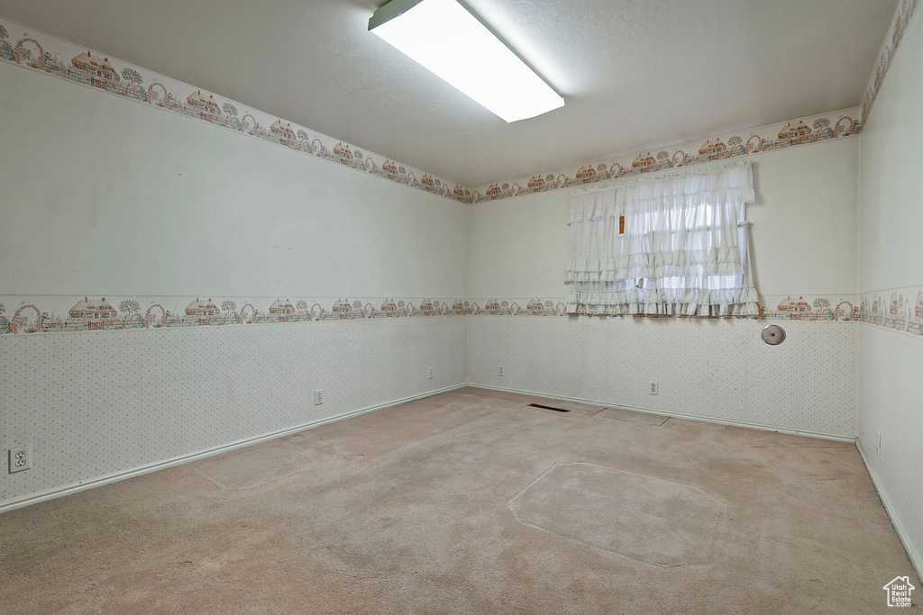 Unfurnished room featuring carpet and a wainscoted wall
