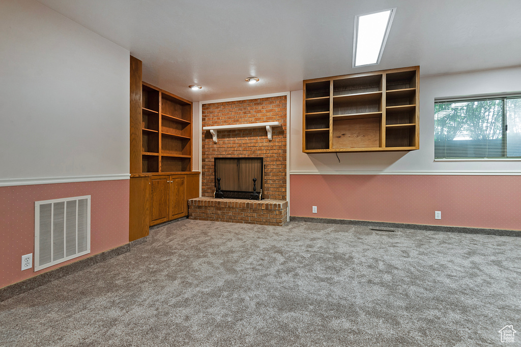 Unfurnished living room featuring a brick fireplace and carpet floors