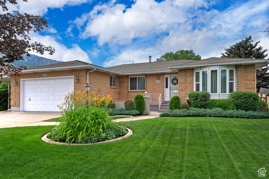 Single story home with a garage, concrete driveway, a front yard, and brick siding