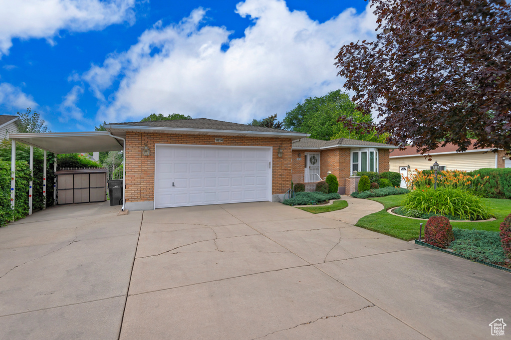 View of front facade with driveway, an attached garage, brick siding, and a carport